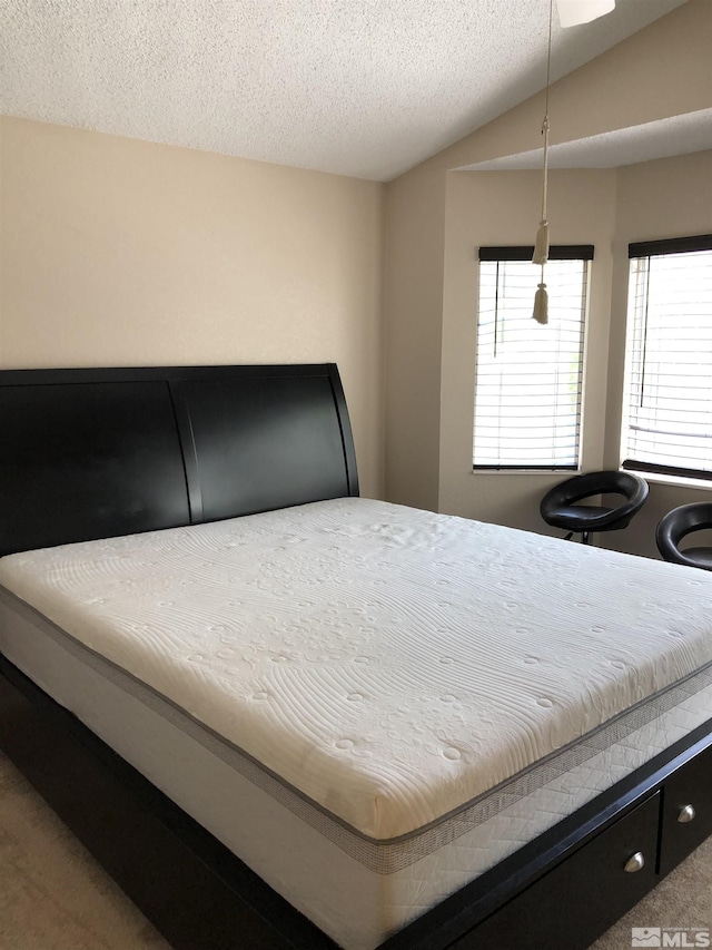 bedroom with vaulted ceiling, multiple windows, and a textured ceiling