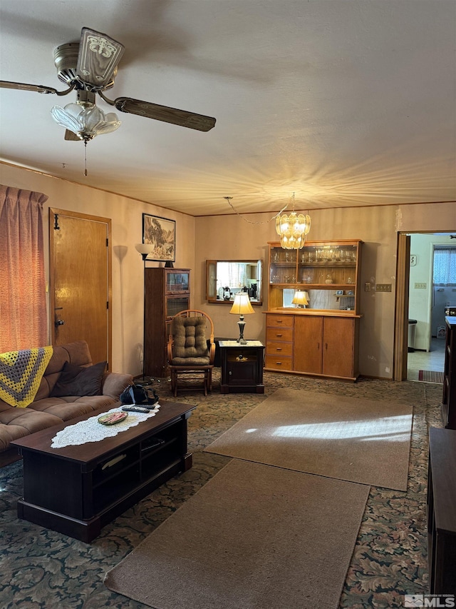 carpeted living room with ceiling fan with notable chandelier