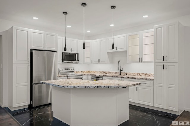 kitchen featuring stainless steel appliances, a kitchen island, light stone countertops, and white cabinets