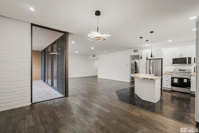 kitchen with white cabinetry, stainless steel appliances, light stone countertops, a kitchen island, and decorative light fixtures