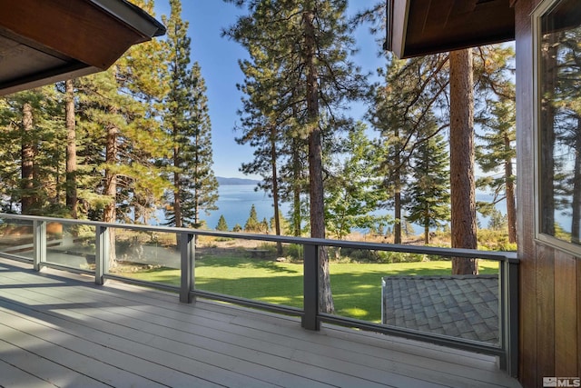 wooden terrace with a water view and a yard