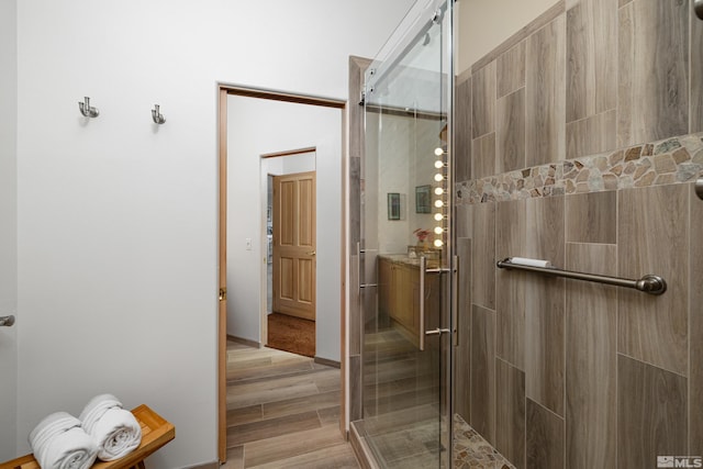 bathroom with hardwood / wood-style flooring and a shower with shower door