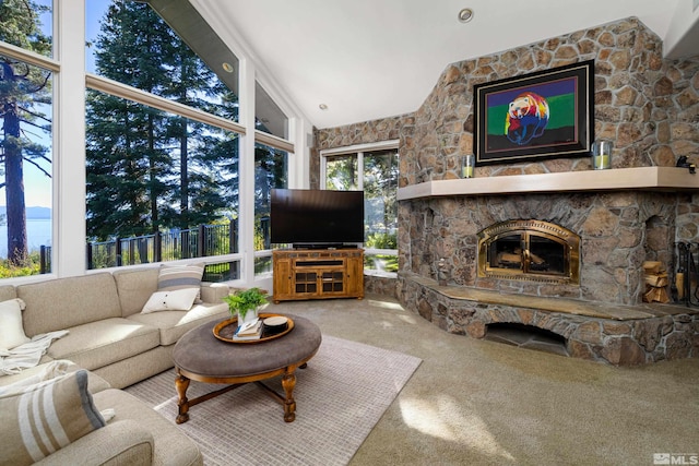 living room featuring lofted ceiling, a fireplace, a water view, and carpet