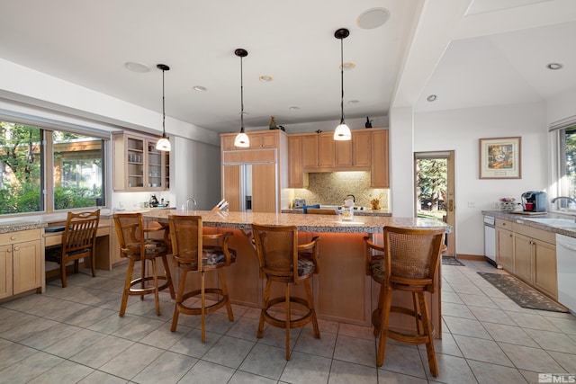 kitchen with tasteful backsplash, a healthy amount of sunlight, a breakfast bar, and paneled built in refrigerator