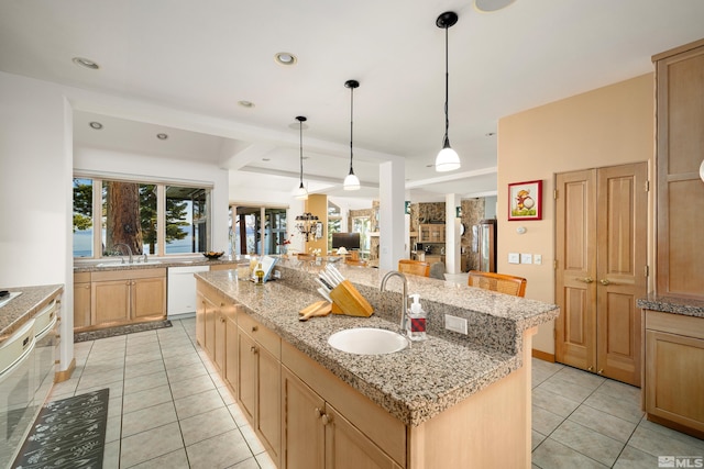 kitchen with pendant lighting, sink, dishwasher, and an island with sink