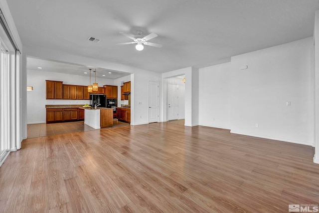 unfurnished living room featuring sink, ceiling fan, and light wood-type flooring