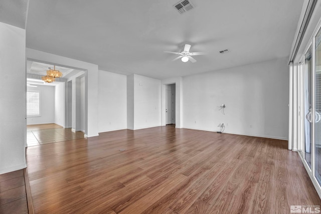 spare room featuring wood-type flooring and ceiling fan with notable chandelier