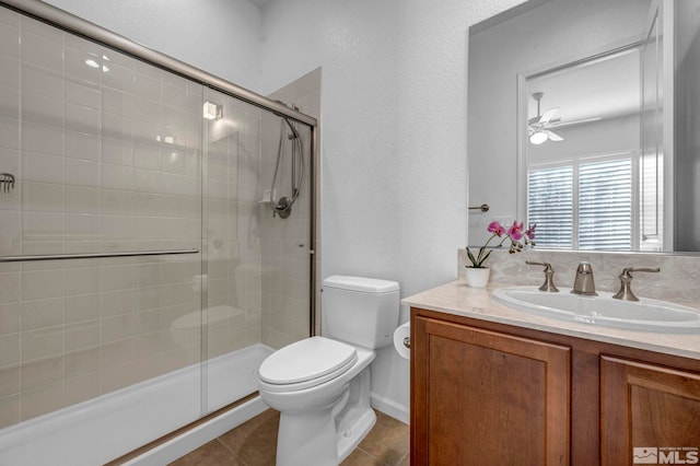 bathroom featuring toilet, an enclosed shower, vanity, ceiling fan, and tile patterned flooring