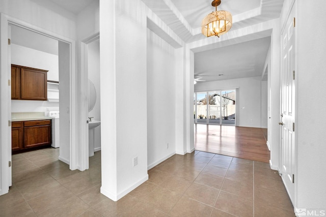 hallway featuring an inviting chandelier and light tile patterned floors