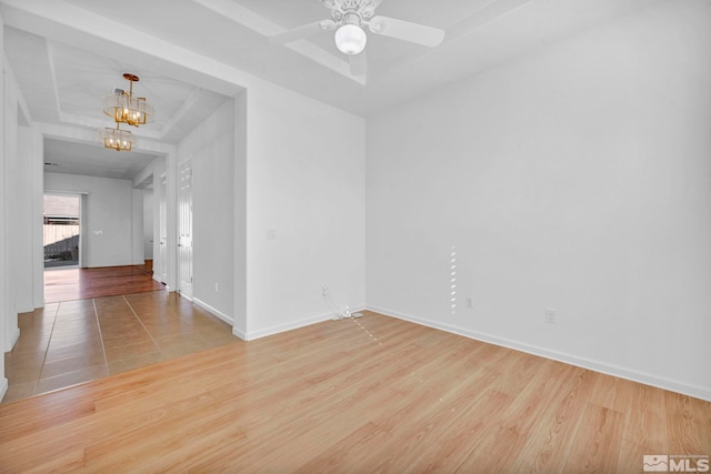 empty room with ceiling fan with notable chandelier and light wood-type flooring