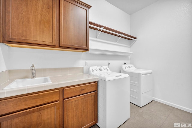 laundry area featuring cabinets, separate washer and dryer, sink, and light tile patterned floors