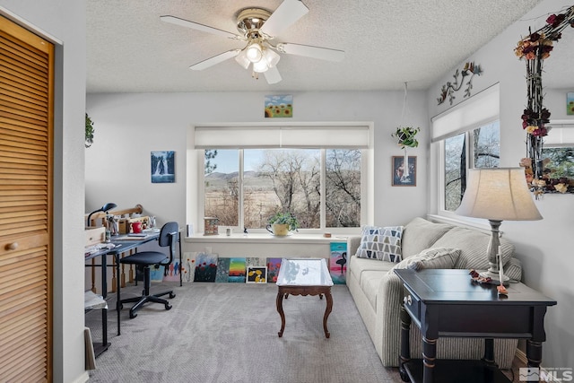 carpeted living room featuring ceiling fan and a textured ceiling