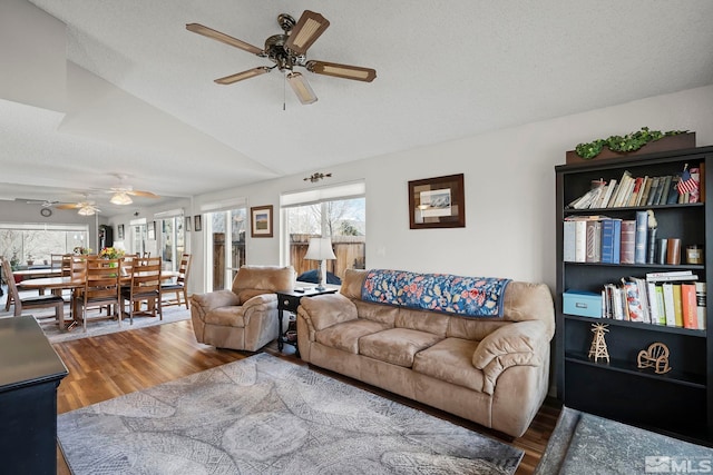 living room featuring ceiling fan, lofted ceiling, hardwood / wood-style floors, and a textured ceiling