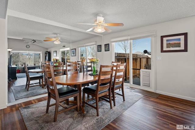 dining area with dark wood-type flooring, lofted ceiling, and a textured ceiling