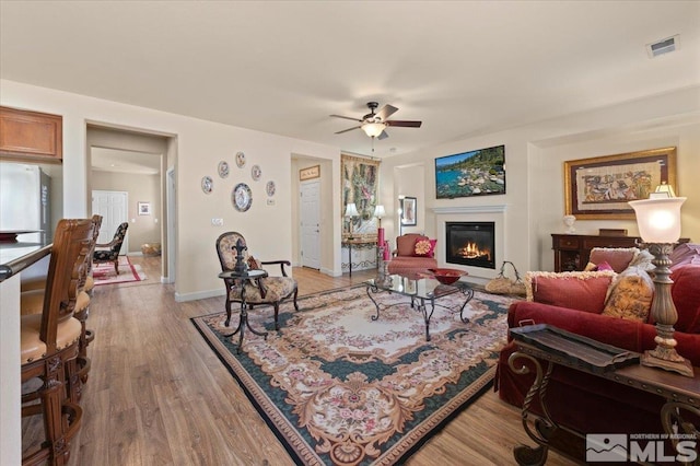 living room featuring ceiling fan and light hardwood / wood-style flooring