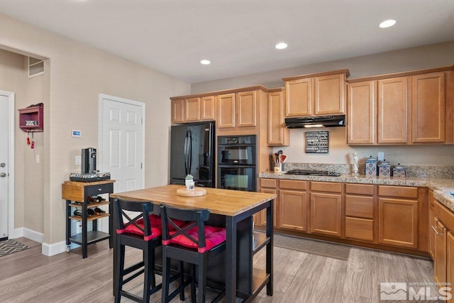 kitchen with light stone countertops, light wood-type flooring, and black appliances