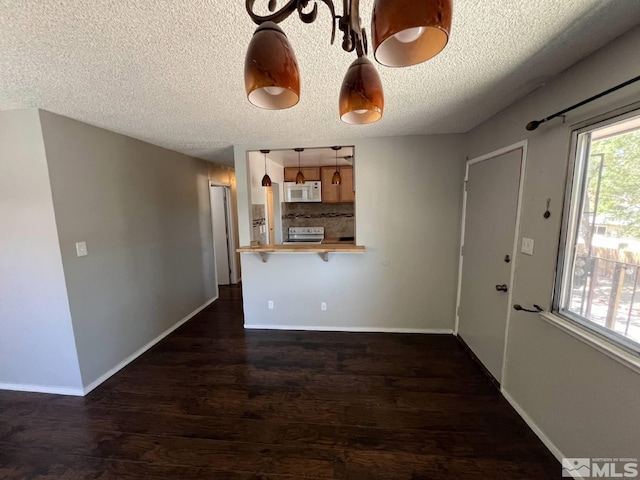 interior space with stainless steel range with electric cooktop, dark hardwood / wood-style flooring, a kitchen breakfast bar, hanging light fixtures, and kitchen peninsula