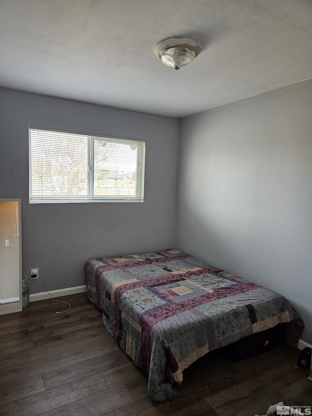 bedroom featuring dark wood-type flooring and a textured ceiling