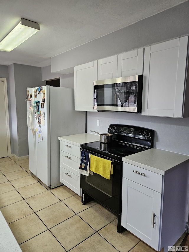 kitchen featuring black range with electric stovetop, light tile patterned floors, white refrigerator with ice dispenser, and white cabinets