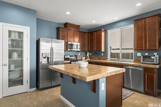 kitchen with tile countertops, sink, a kitchen breakfast bar, a center island, and stainless steel appliances