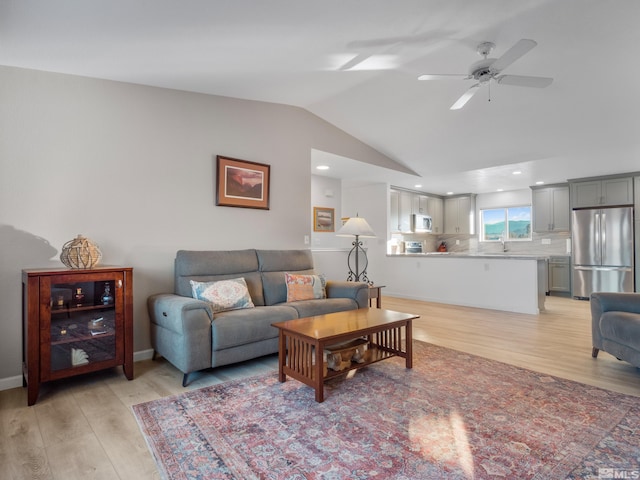 living room with lofted ceiling, sink, ceiling fan, and light wood-type flooring