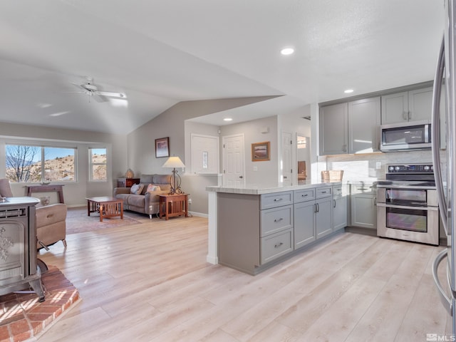 kitchen with appliances with stainless steel finishes, gray cabinetry, light hardwood / wood-style floors, and kitchen peninsula