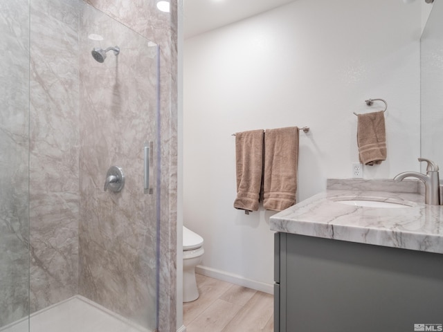 bathroom featuring toilet, a shower with door, and hardwood / wood-style floors