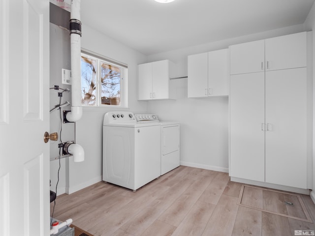 laundry room with cabinets, washer and dryer, and light hardwood / wood-style floors