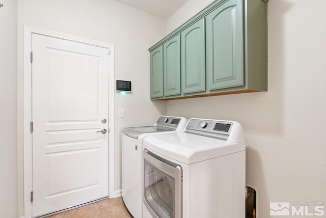 laundry area featuring cabinets, light tile patterned floors, and washer and clothes dryer