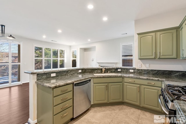 kitchen with sink, dark stone counters, kitchen peninsula, green cabinets, and stainless steel appliances