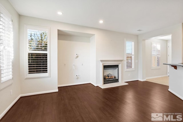 unfurnished living room featuring a healthy amount of sunlight and dark hardwood / wood-style flooring