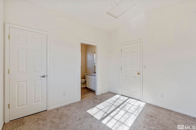 unfurnished bedroom featuring light carpet and ensuite bath