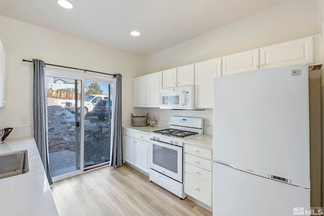 kitchen featuring white cabinetry, sink, white appliances, and light hardwood / wood-style flooring