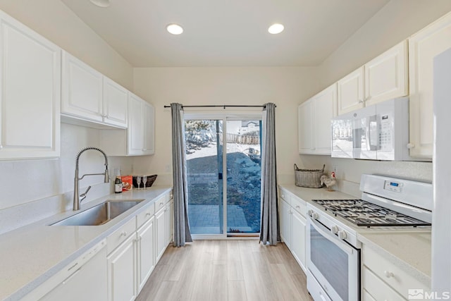 kitchen with white cabinetry, sink, and white appliances