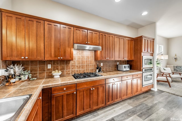 kitchen featuring tasteful backsplash, sink, stainless steel appliances, and light hardwood / wood-style floors