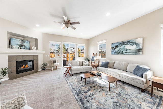 living room with a tiled fireplace, ceiling fan, and carpet