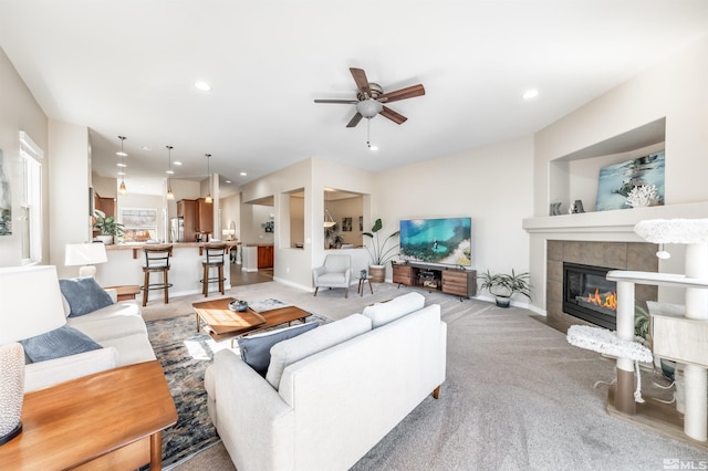 carpeted living room featuring a tile fireplace and ceiling fan