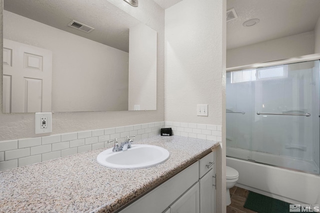 full bathroom featuring vanity, a textured ceiling, toilet, and combined bath / shower with glass door