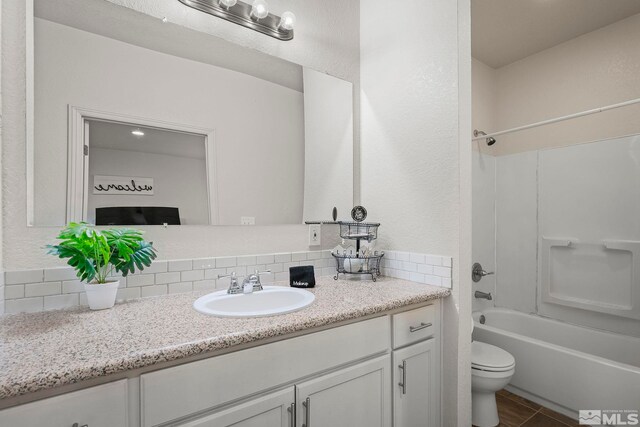 full bathroom featuring washtub / shower combination, vanity, toilet, and decorative backsplash