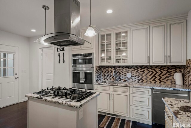 kitchen with sink, appliances with stainless steel finishes, light stone countertops, island exhaust hood, and decorative light fixtures