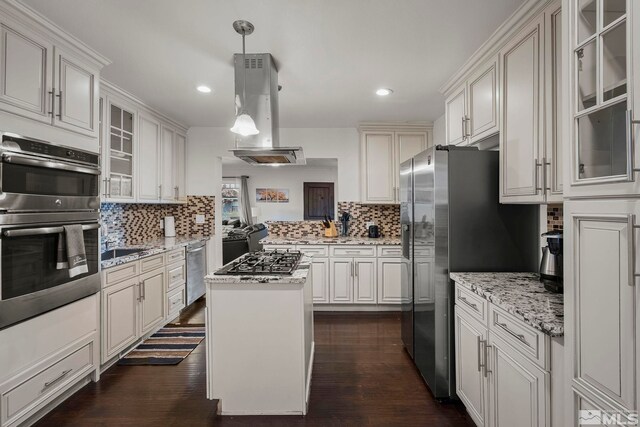 kitchen featuring a kitchen island, island range hood, pendant lighting, stainless steel appliances, and light stone countertops