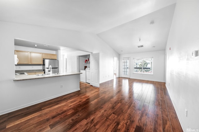 unfurnished living room featuring separate washer and dryer, sink, lofted ceiling, and dark hardwood / wood-style flooring