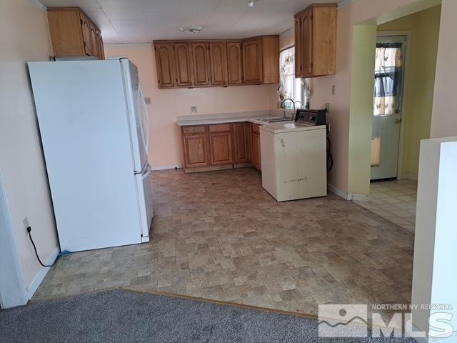 kitchen featuring white refrigerator, washer / dryer, and sink