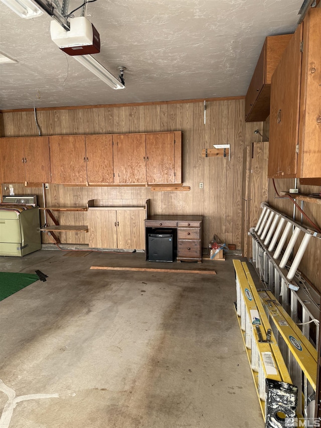 garage with a garage door opener, fridge, wooden walls, and washer / clothes dryer