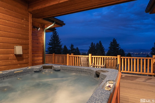 deck at dusk with an outdoor hot tub