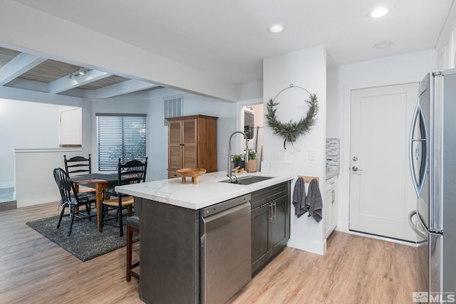 kitchen featuring sink, beam ceiling, stainless steel appliances, and light hardwood / wood-style floors