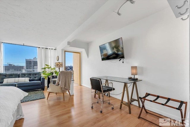 bedroom with a wall of windows, a textured ceiling, and light hardwood / wood-style flooring