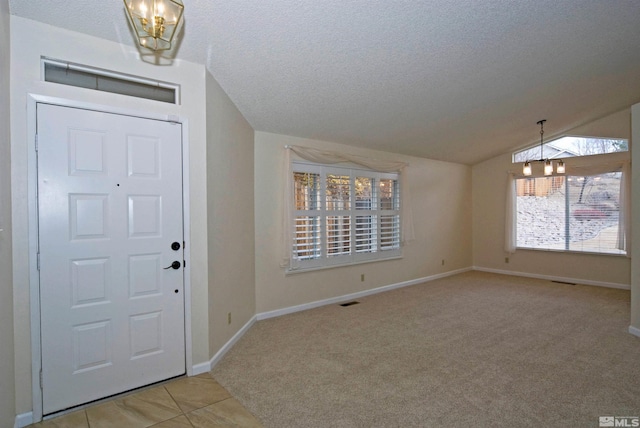 carpeted foyer featuring an inviting chandelier, lofted ceiling, and a textured ceiling