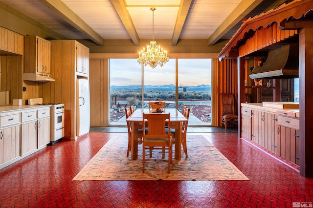 dining space with an inviting chandelier, wooden walls, beam ceiling, and a mountain view