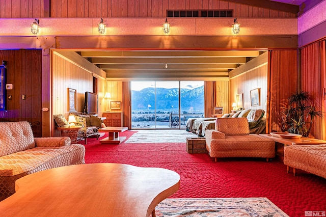 carpeted living room with vaulted ceiling with beams and wood walls